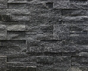 Black stone cladding wall made with  different shape blocks. Background and texture.