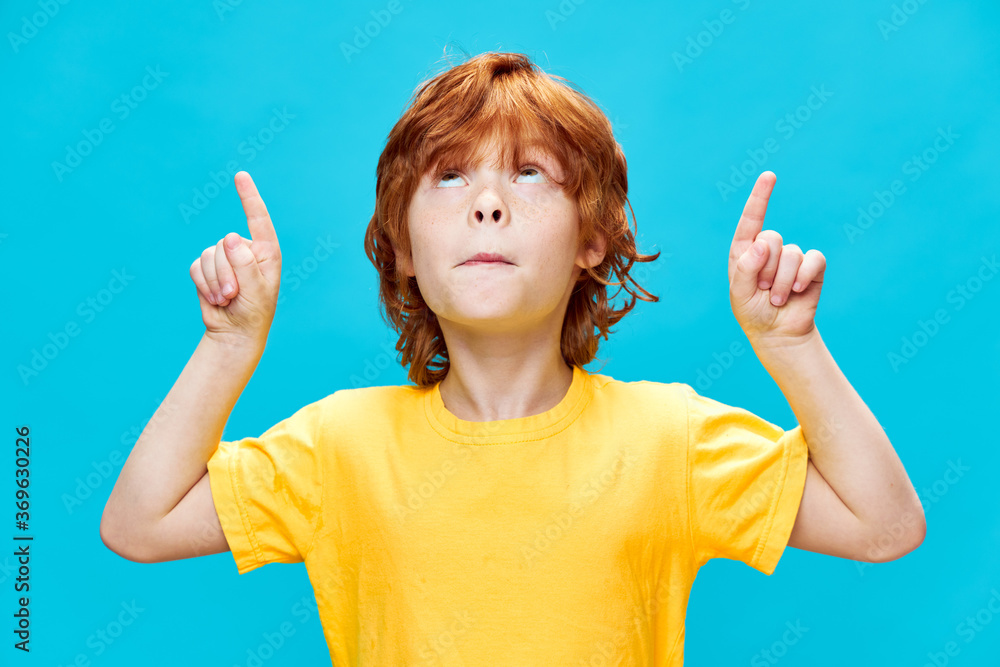 Sticker child with red hair points up with index finger copy space