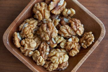 Walnuts kernels on dark desk with color background, Whole walnut in wood vintage bowl.