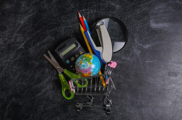 Preschool shopping. Supermarket trolley with school supplies on a chalk board. Top view