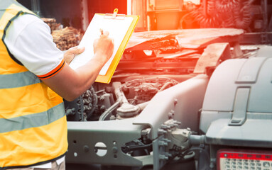 A truck driver holding clipboard his checking safety a semi truck.
