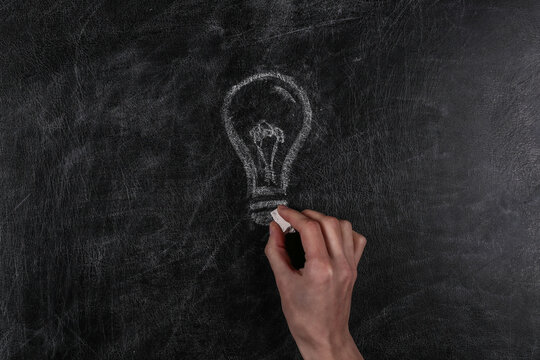 Hand draws a light bulb on a chalk board. I have an idea!