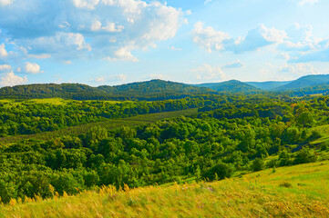 Obraz premium Beautiful fields against the backdrop of mountains and blue sky with clouds.