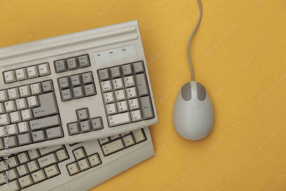 Poster old keyboard and pc mouse on yellow background. top view. flat lay