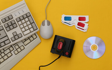 Obraz na płótnie Canvas Flat lay 90s attribute composition. PC keyboard, mouse, gamepads, CD, 3D glasses. Retro Electronics, gadgets and devices. Entertainment and gaming. Yellow background. Top view