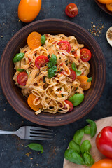Marinara pasta on a brown clay plate with tomato slices and Basil leaves