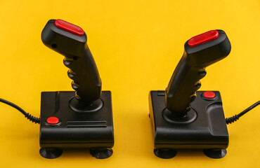 Two retro joysticks on yellow background. Gaming, video game competition.