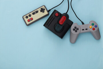 Retro gamepads and joysticks on blue background. Video game, gaming 80s. Flat lay, top view. Copy...