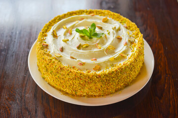Sweet pistachio dessert with vanilla cream and nuts on white plate. Slice of pistachio cake. Tea time.