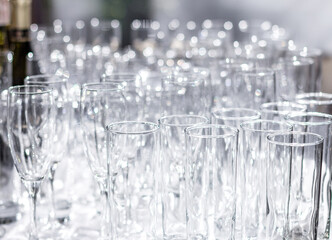 Lots of different empty glasses on the table. Preparing for a banquet, holiday or wedding. Blurred back.
