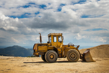 Bulldozer working on a mountain with beautiful clouds in the background