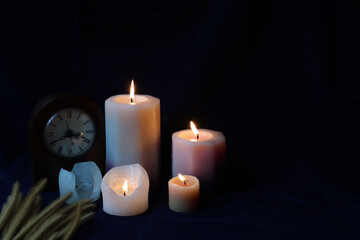 Fototapeta na wymiar candles flame and vintage clock in the dark background