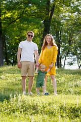Fototapeta premium Family life. Portrait of parents and their son on the background of nature. Walk in park. Happy family leisure outdoors.