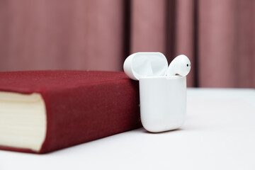 Wireless headphones in an old book with copy space, concept of audiobook, self-study.