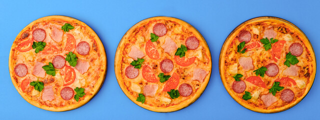 Three pizzas on the blue azure background. Pizza isolated. Banner with copy space for text or logo. Italian cuisine.
