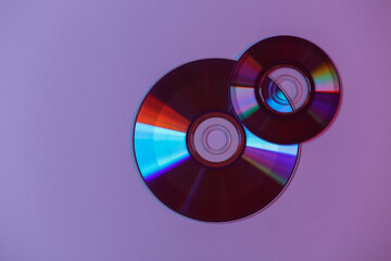 CD's in red blue gradient neon light. Top view.