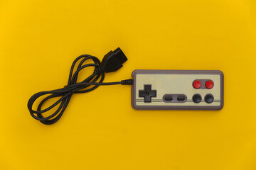 Wired retro gamepad (joystick) with wound cable on yellow background. Video game, gaming. Top view