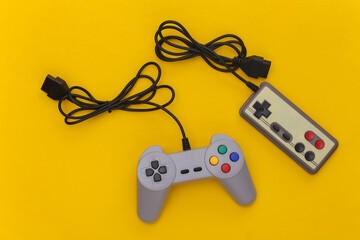 Wired retro gamepads (joysticks) with wound cable on yellow background. Video game, gaming. Top view © splitov27