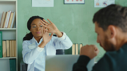 Doctor appointment. Scared female doctor covering herself social distancing unhealthy man patient coughing. Hospital office. Health care, pandemic, virus infections.