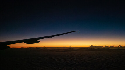 The view of airplane wing with beautiful sunrise at horizon sky background.