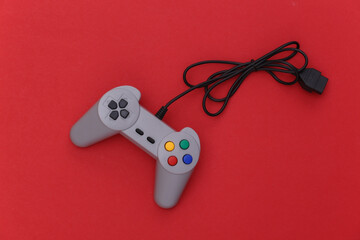 Wired retro gamepad (joystick) with wound cable on red background. Video game, gaming. Top view © splitov27