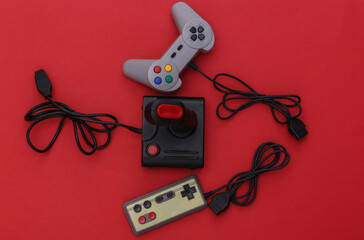 Wired retro gamepads and joystick with wound cable on red background. Video game, gaming. Top view