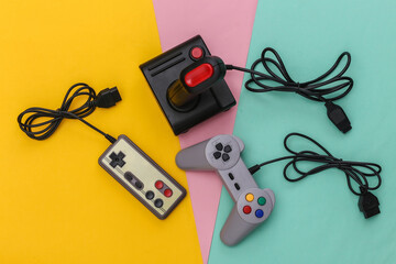 Wired retro gamepads and joystick with wound cable on colored background. Video game, gaming. Top view