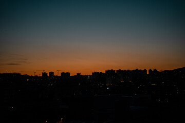Skyline de ciudad al atardecer con tonos anaranjados