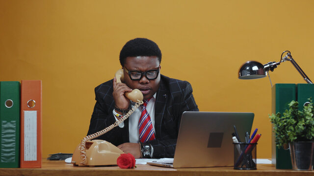 Smart attentive afro-american executive talks on telephone call solving business tasks problem using smartphone device calling at modern office corporation.