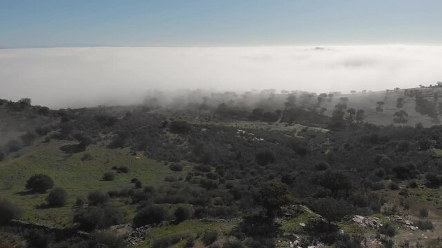 Spectacular Landscape Scenic View Of White Blanket Of Clouds Above Alqueva Rough And Rocky Ground With Outcroppings Of Green Trees And Vegetation On Sunny Day, Portugal, Overhead Aerial Backward