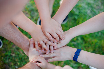 Close up of a kids and adults hands together in circle laying one on another