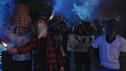 Aggressive black leader walking in front of riot crowd, shouting slogans at policemen, fighting...