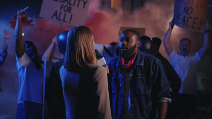 Female TV journalist interviews black man strike leader making loud message speech in front of emotional crowd. Protest for human rights. Black lives matter.