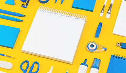 Assorted office and school white and blue stationery on bright yellow background. Organized...