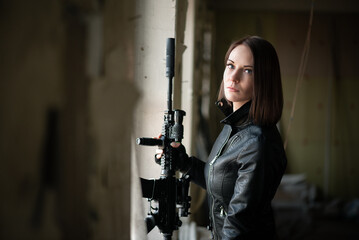 Concept of special force woman with a airsoft rifle on abandoned building background.