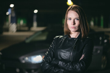 Fototapeta premium A young pretty girl is standing on a car background.