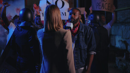 Female TV journalist interviews black man strike leader making loud message speech in front of emotional crowd. Protest for human rights. Black lives matter.