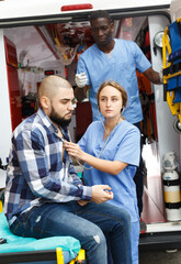Fototapeta na wymiar Emergency doctors providing medical care to injured man in ambulance car