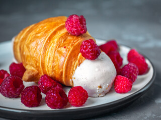 Pastry with berries, croissant and fresh raspberries on a light plate close-up