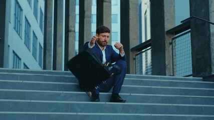 Frustrated office worker sitting on stairs in despair after job loss. Unemloyed young businessman manager executive being sad on day of dismissal. Economic crisis. Layoff.