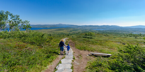 Mother and son walk down a mountain path in the Norwegian mountains