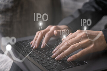 Businesswoman typing on computer in office. IPO icon hologram. Double exposure.