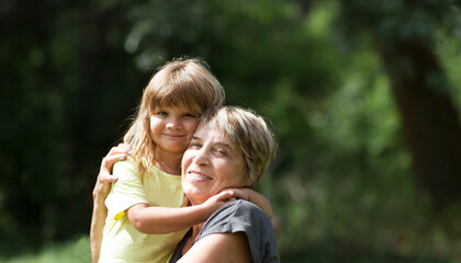 Child girl embracing Grandmother  spending time together in nature. Concept of friendly family. Quality Time. copy space 
