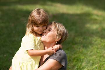 Child girl embracing Grandmother  spending time together in nature. Concept of friendly family....