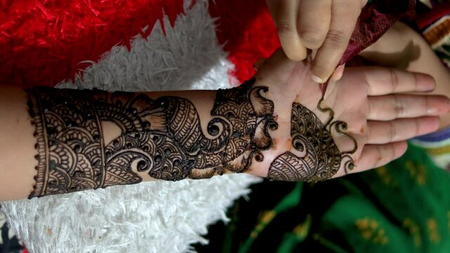 Closeup of Woman designing Henna or Mehendi Tattoo on the palm of a girl