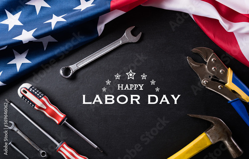 Happy Labor day concept. American flag with different construction tools on black table background, with copy space for text.