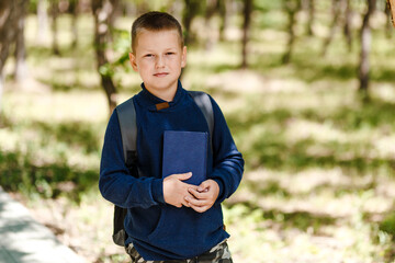 eight-year-old boy with a backpack and a book in his hand