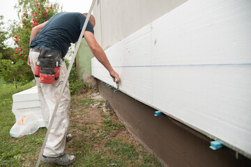 Construction worker working on a house facade using a string tool to check the level