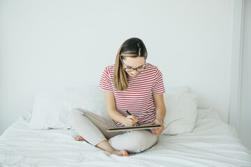 Girl digital artist draws with a stylus on a tablet or laptop. She is a student and is studying...