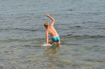 Caucasian kid in the sea in summer lifestyle back view. Child in water on the beach in summer holidays, Active healthy leisure and happy vacation concept